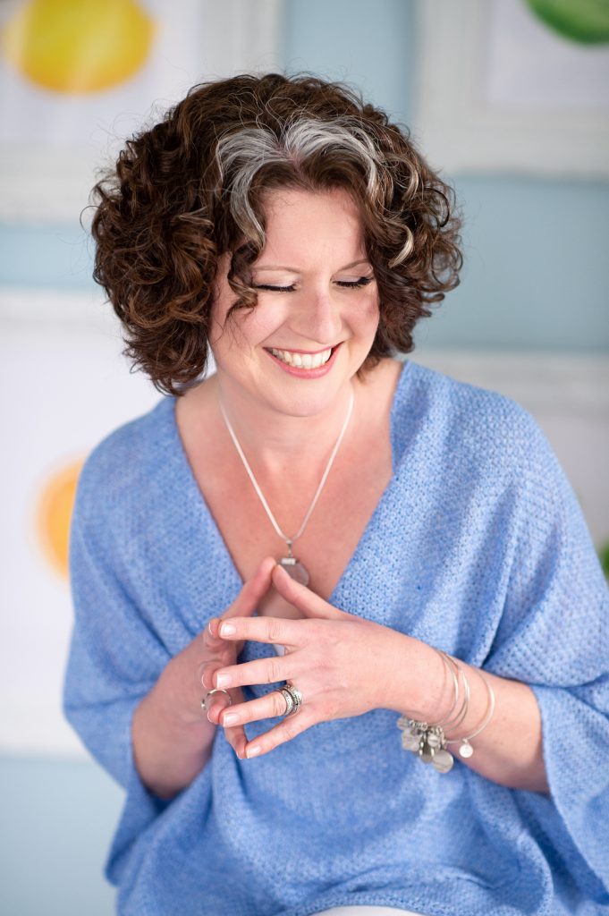 Vickie in a blue shawl clasping her hands together.